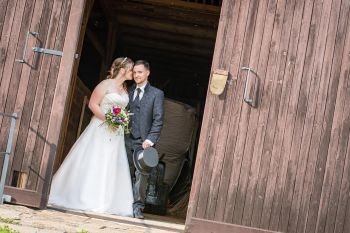 Hochzeitspaar steht in Scheunentuer bei Freier Trauung