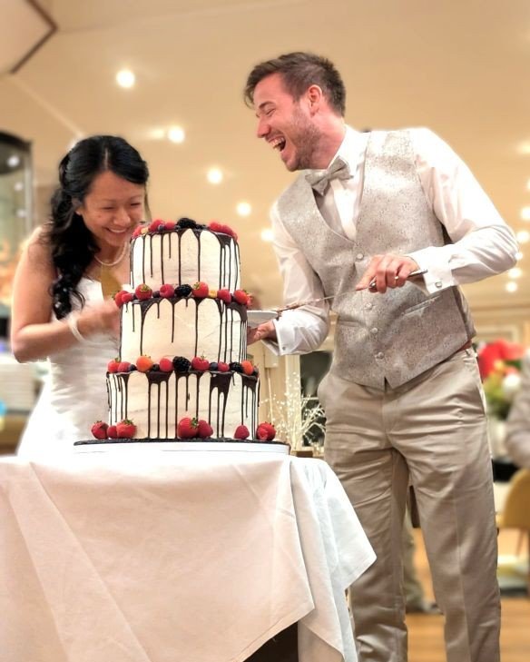 Brautpaar schneidet im Strandhotel schoene Hochzeitstorte an